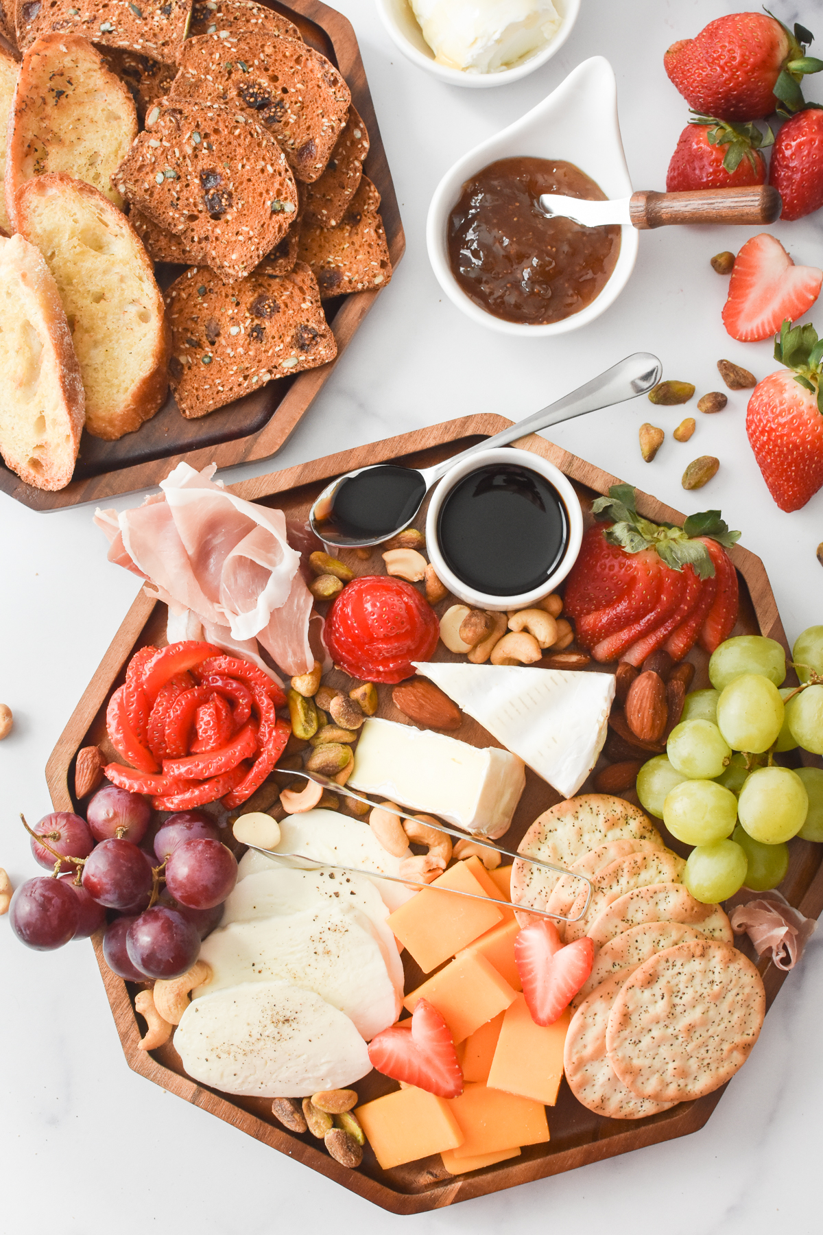 A charcuterie board featuring strawberries cut 4 different ways.
